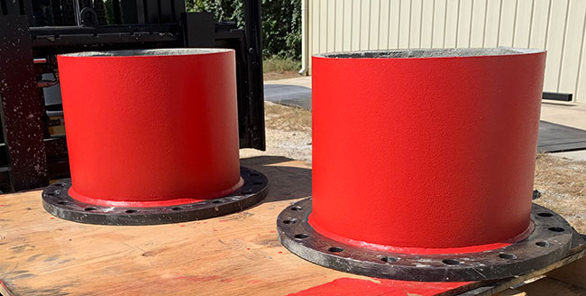 Custom fabricated red pipeline fittings staged for delivery