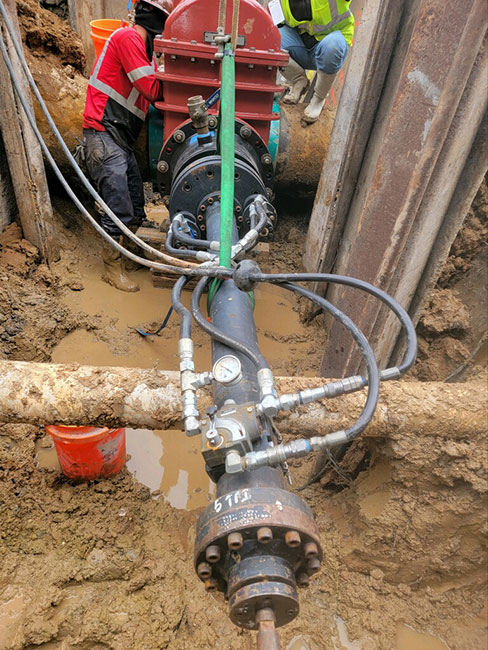 Crew operating line stop equipment on a large main inside a shored excavation