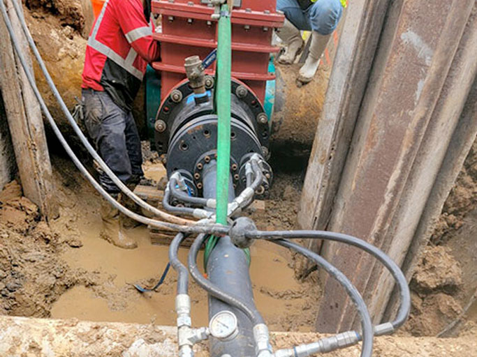 Hydraulic equipment attached to a repaired pressure pipe in an excavation